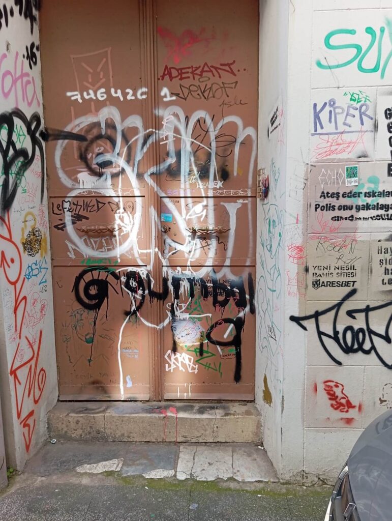 graffiti e scritte sovrapposte su una porta a Kadıköy street art urbana